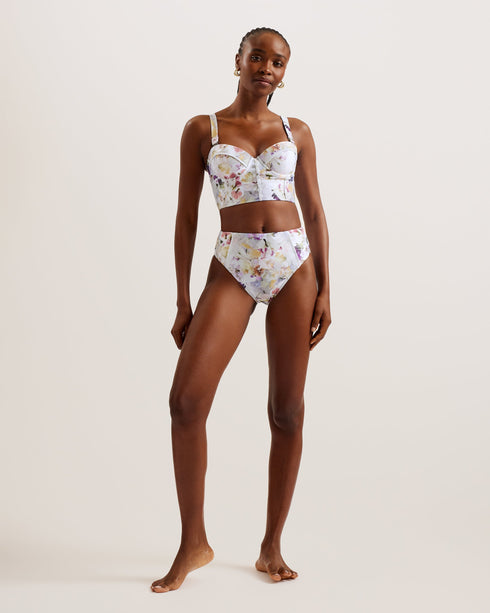 ULANIA-Swimwear-The ULANIA bikini top makes for sweet swimwear with a pressed floral print and faux button detailing down its longline design. Underwire and padding on the bust create a flattering and supportive fit, with removable straps for versatile style. It fastens at the back with a branded hook, finished with a playful cut-out detail. Longline bikini top Pressed floral print Faux button detail Back cut out Padded cups with underwire Removable and adjustable straps Hook fastening Lydia is 5'10" / 1.77