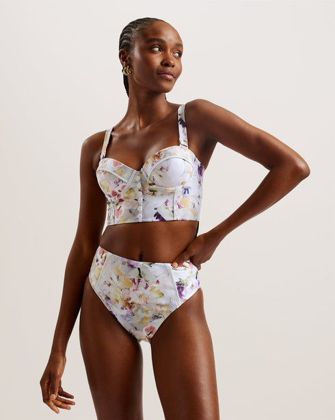 ULANIA-Swimwear-The ULANIA bikini top makes for sweet swimwear with a pressed floral print and faux button detailing down its longline design. Underwire and padding on the bust create a flattering and supportive fit, with removable straps for versatile style. It fastens at the back with a branded hook, finished with a playful cut-out detail. Longline bikini top Pressed floral print Faux button detail Back cut out Padded cups with underwire Removable and adjustable straps Hook fastening Lydia is 5'10" / 1.77