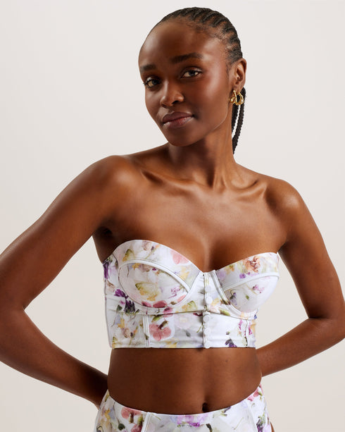 ULANIA-Swimwear-The ULANIA bikini top makes for sweet swimwear with a pressed floral print and faux button detailing down its longline design. Underwire and padding on the bust create a flattering and supportive fit, with removable straps for versatile style. It fastens at the back with a branded hook, finished with a playful cut-out detail. Longline bikini top Pressed floral print Faux button detail Back cut out Padded cups with underwire Removable and adjustable straps Hook fastening Lydia is 5'10" / 1.77