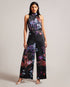 MARLEEH-Trousers-Dress to impress in MARLEEH. Featuring an oversized neck tie and a fitted waist, this sleeveless jumpsuit offers a sophisticated and flattering fit. Satin jumpsuit Floral print Wide leg Sleeveless Oversized neck tie Stand collar Fitted waist Zip fastening Samruddhi is 5'7" / 1.71m and wears Black in a Ted size 1- Ted Baker Romania